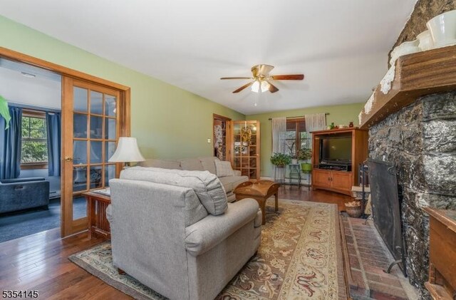 living room with a fireplace, a ceiling fan, and wood finished floors
