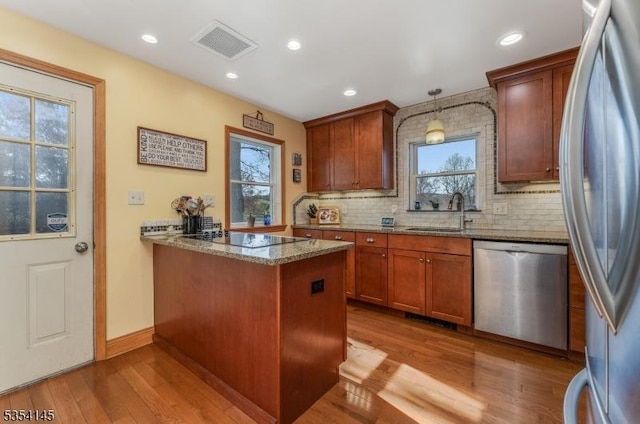 kitchen with appliances with stainless steel finishes, a sink, visible vents, and wood finished floors