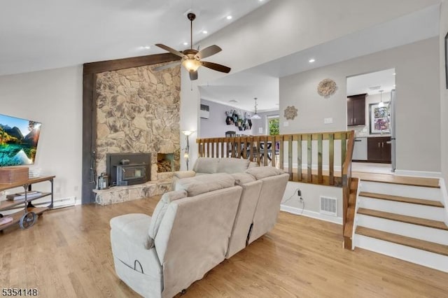 living area featuring ceiling fan, light wood finished floors, baseboards, vaulted ceiling, and visible vents