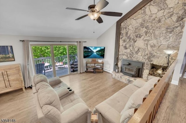 living room featuring ceiling fan, a wood stove, high vaulted ceiling, baseboards, and wood finished floors
