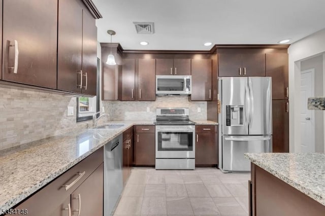 kitchen with dark brown cabinetry, appliances with stainless steel finishes, decorative backsplash, and a sink