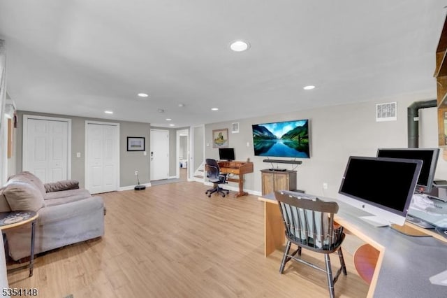living area with visible vents, a wood stove, baseboards, recessed lighting, and light wood-style flooring