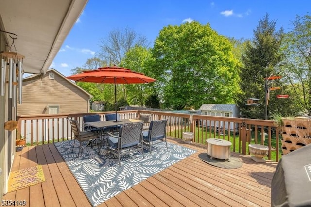 wooden terrace featuring outdoor dining space, an outbuilding, and a shed