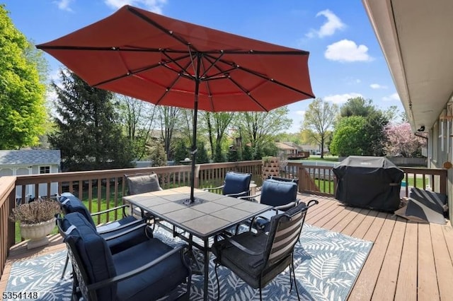 deck with outdoor dining area, an outbuilding, and a grill