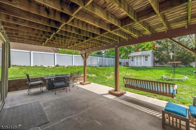 view of patio / terrace with a storage unit, a fenced backyard, an outbuilding, and outdoor dining space