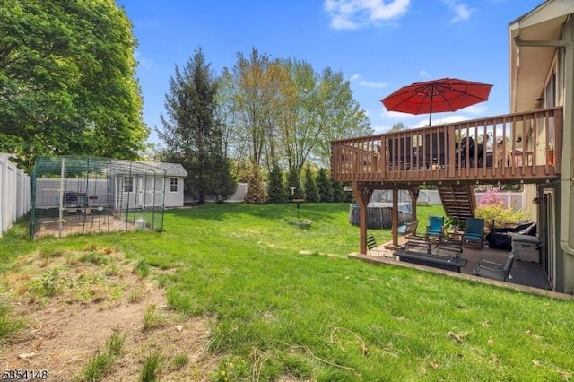view of yard with a wooden deck, stairway, fence, an outdoor structure, and a patio