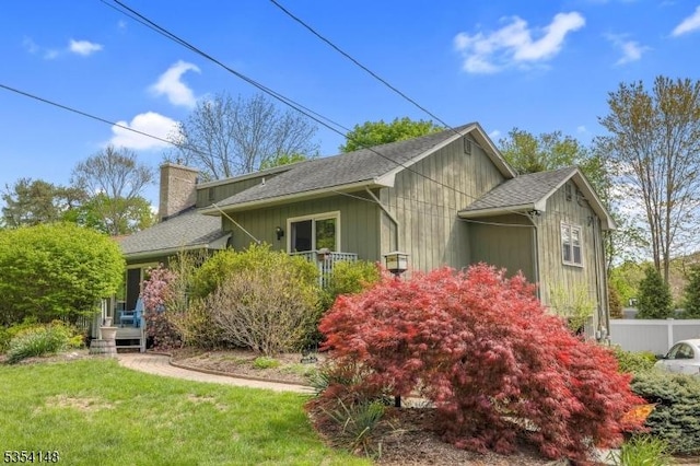 view of home's exterior with fence, a chimney, a yard, and roof with shingles
