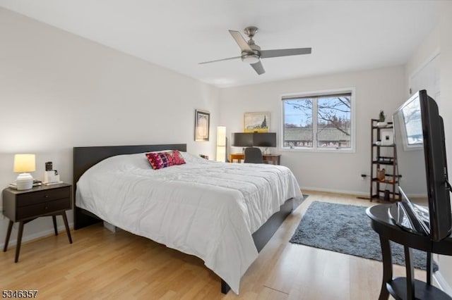 bedroom featuring a ceiling fan, baseboards, and light wood-style floors