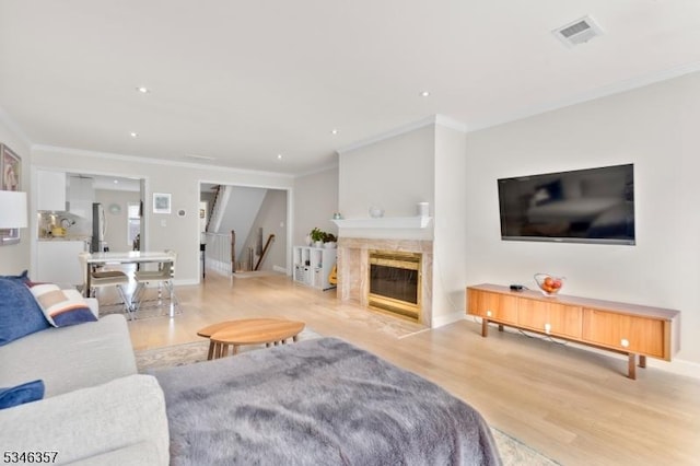 living room with recessed lighting, visible vents, ornamental molding, and light wood finished floors