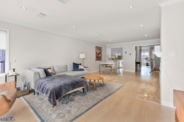 living room with visible vents, ornamental molding, baseboards, recessed lighting, and light wood finished floors
