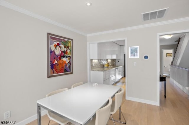 dining area featuring visible vents, ornamental molding, light wood-style floors, and baseboards