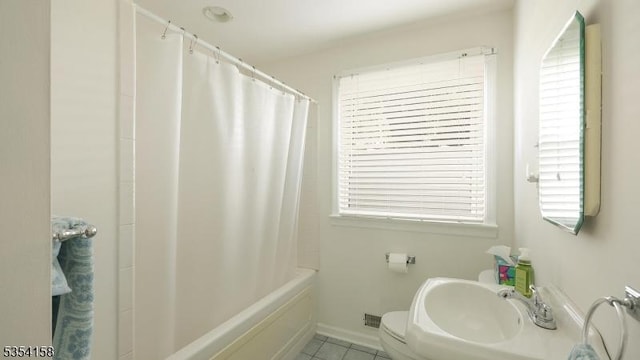 bathroom with tile patterned flooring, toilet, baseboards, a sink, and shower / tub combo