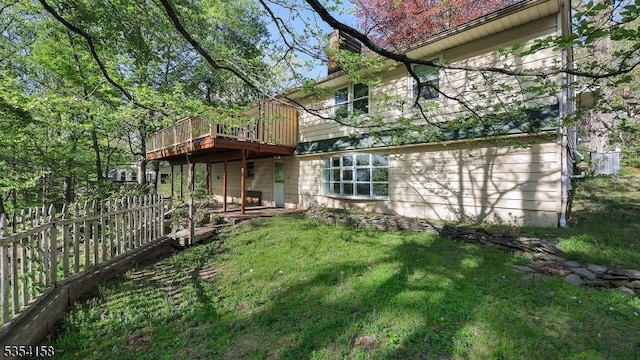 back of house with a yard, a deck, and fence