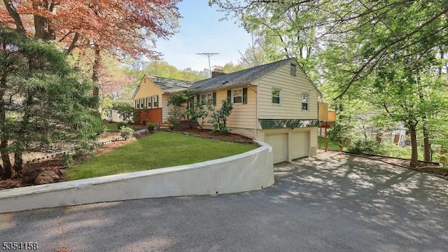view of front of house featuring an attached garage, a front yard, driveway, and a chimney