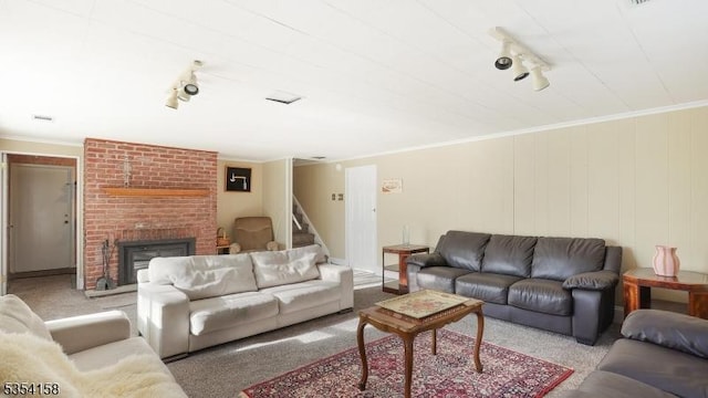 carpeted living area with stairway, crown molding, a brick fireplace, and rail lighting