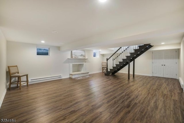 finished basement featuring a fireplace, baseboards, wood finished floors, a baseboard radiator, and stairway