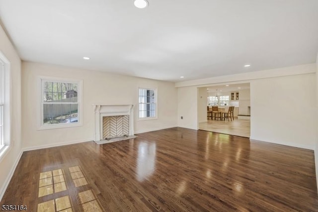 unfurnished living room with baseboards, a fireplace with flush hearth, wood finished floors, and recessed lighting