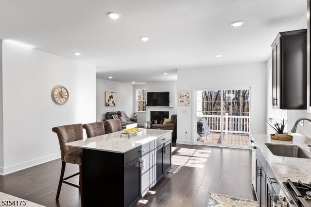 kitchen featuring stainless steel range with electric cooktop, light stone countertops, a breakfast bar, and a sink