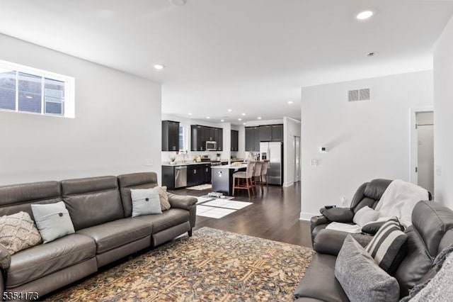 living room with visible vents, recessed lighting, and dark wood finished floors