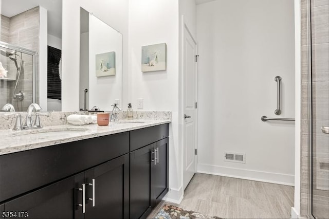 full bath with visible vents, a sink, double vanity, and a shower stall