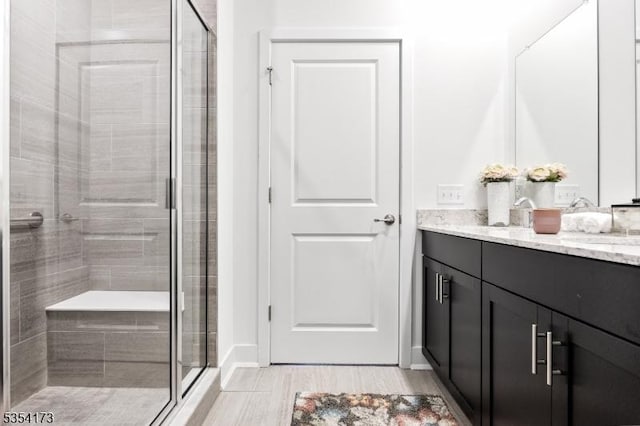 bathroom featuring vanity, baseboards, a shower stall, and wood finished floors