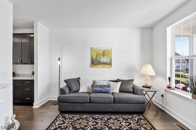 living area featuring baseboards, visible vents, and dark wood-type flooring