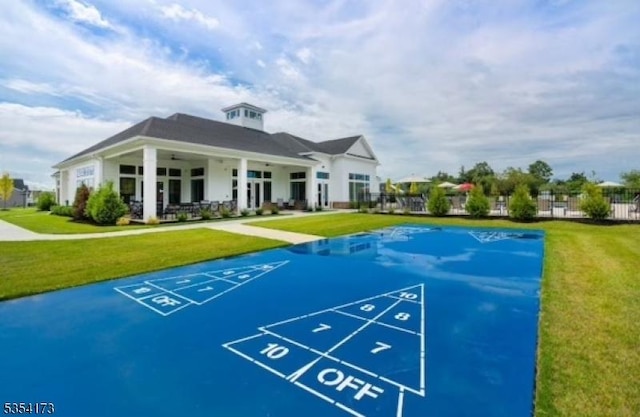 view of community with a lawn, shuffleboard, and fence