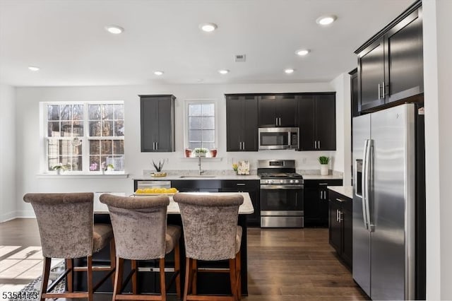 kitchen featuring dark cabinets, light countertops, stainless steel appliances, and a sink