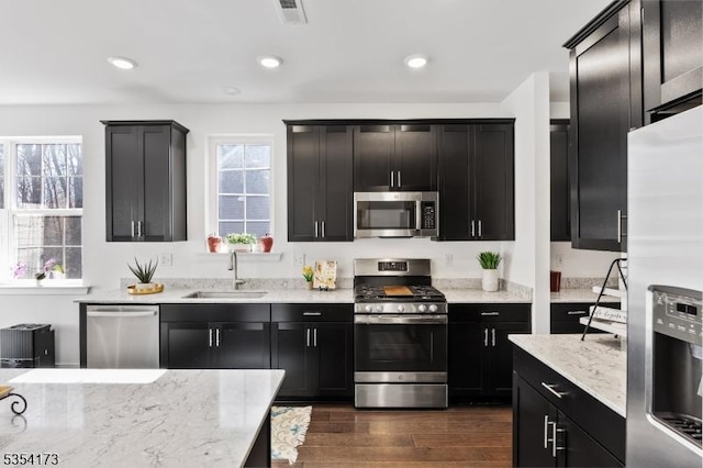 kitchen featuring dark cabinets, a sink, appliances with stainless steel finishes, and visible vents