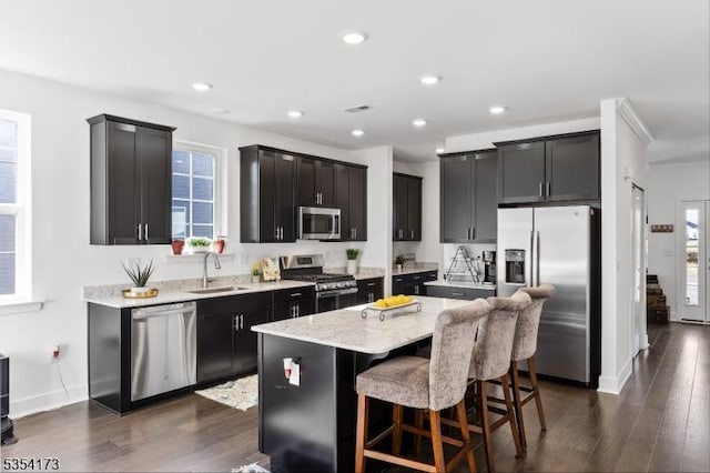 kitchen with appliances with stainless steel finishes, a wealth of natural light, a sink, and a center island