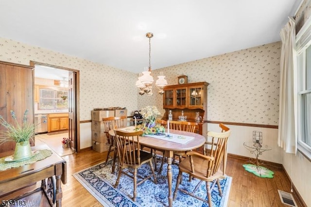 dining space featuring wallpapered walls, a notable chandelier, and light wood-style floors