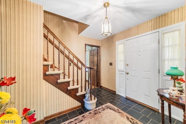 entryway with an inviting chandelier, baseboards, stairway, wallpapered walls, and dark tile patterned floors