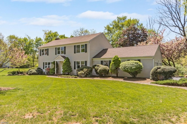 colonial home featuring a shingled roof and a front yard