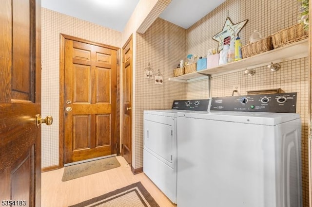 washroom featuring laundry area, wallpapered walls, light wood-style flooring, and washing machine and clothes dryer