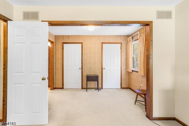 interior space with baseboards, light carpet, and visible vents