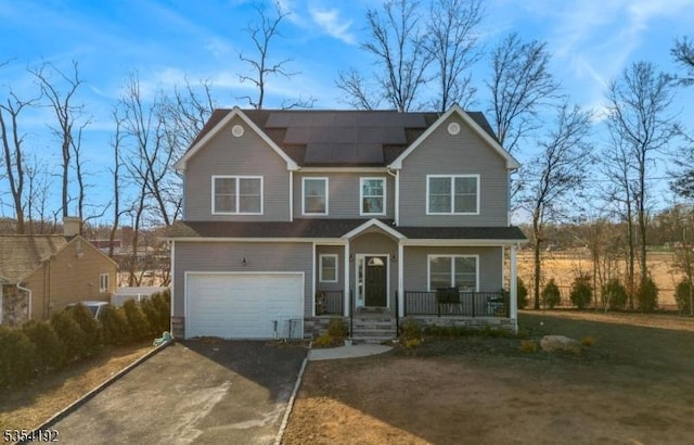 traditional-style house featuring a garage, solar panels, a porch, and aphalt driveway