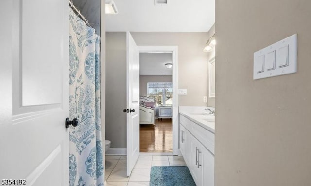 ensuite bathroom featuring connected bathroom, toilet, tile patterned floors, and vanity
