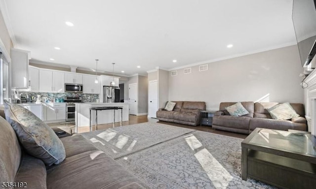 living area featuring visible vents, recessed lighting, and ornamental molding