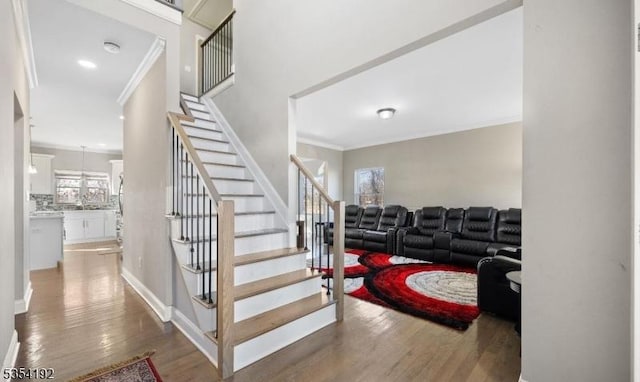 stairway featuring crown molding, baseboards, and wood finished floors