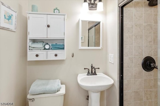 bathroom with toilet, a sink, and tiled shower