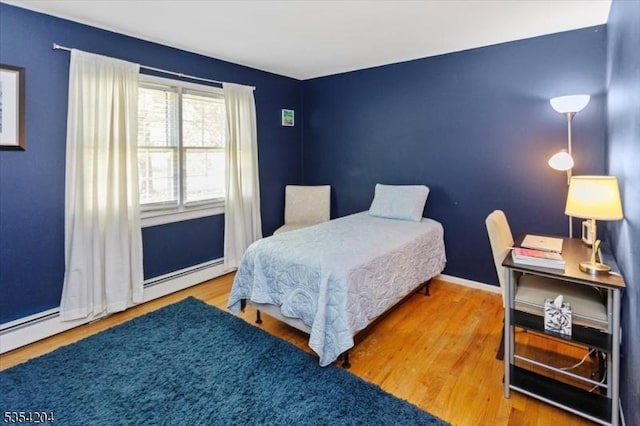 bedroom with baseboards, wood finished floors, and a baseboard radiator