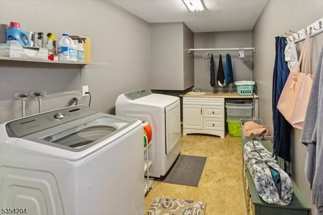 clothes washing area with a sink, cabinet space, and independent washer and dryer