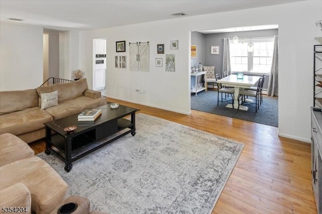 living room with baseboards, light wood-style flooring, and visible vents