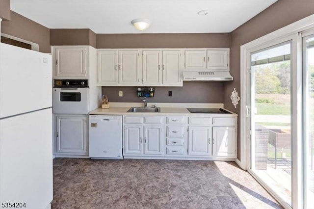 kitchen featuring white cabinets, a sink, white appliances, light countertops, and under cabinet range hood