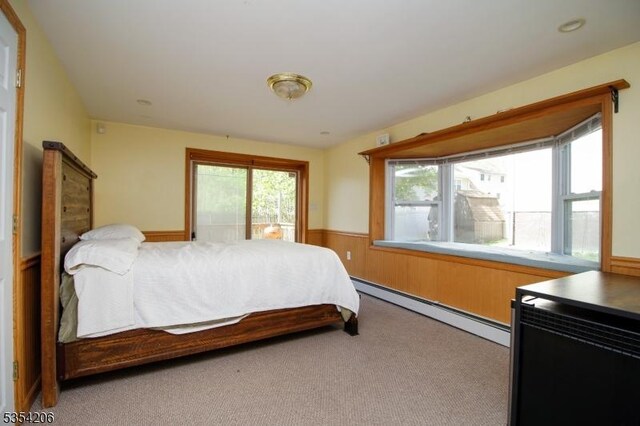 carpeted bedroom with a wainscoted wall and baseboard heating