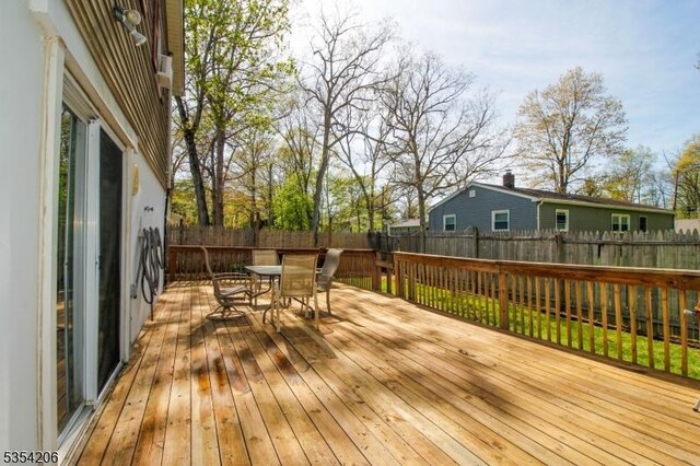 wooden terrace with outdoor dining space and a fenced backyard