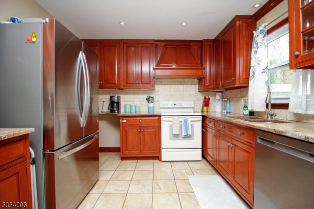 kitchen with decorative backsplash, custom range hood, light tile patterned floors, a sink, and stainless steel appliances