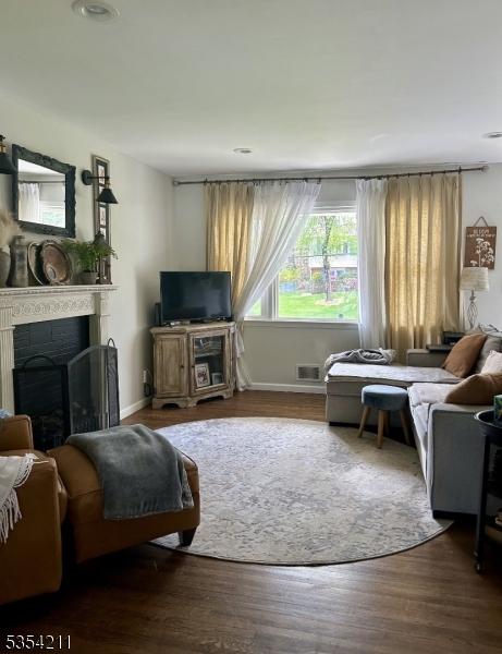 living room with baseboards, a fireplace, wood finished floors, and visible vents