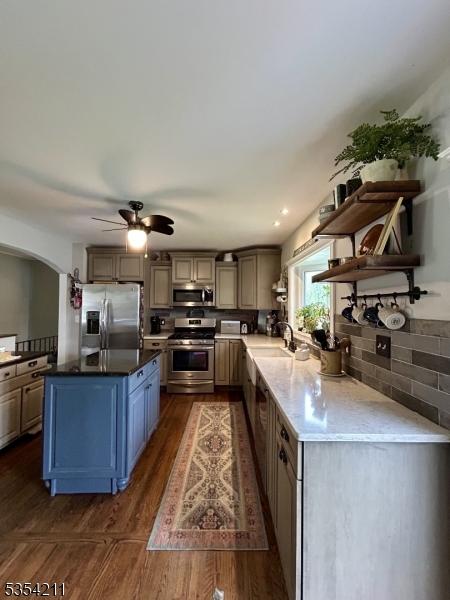 kitchen featuring open shelves, decorative backsplash, ceiling fan, dark wood-style floors, and appliances with stainless steel finishes