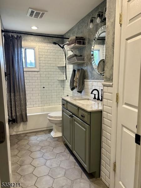 bathroom with visible vents, vanity, tile patterned floors, toilet, and shower / tub combo with curtain